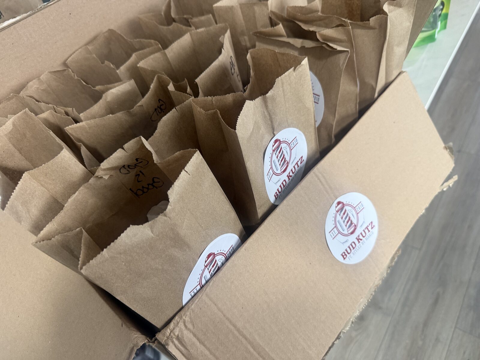 Box of packed lunch bags sealed with Bud Kutz logo stickers